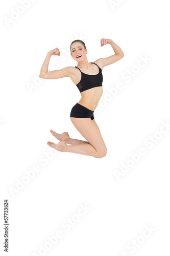 Strong slim model jumping in the air flexing her muscles