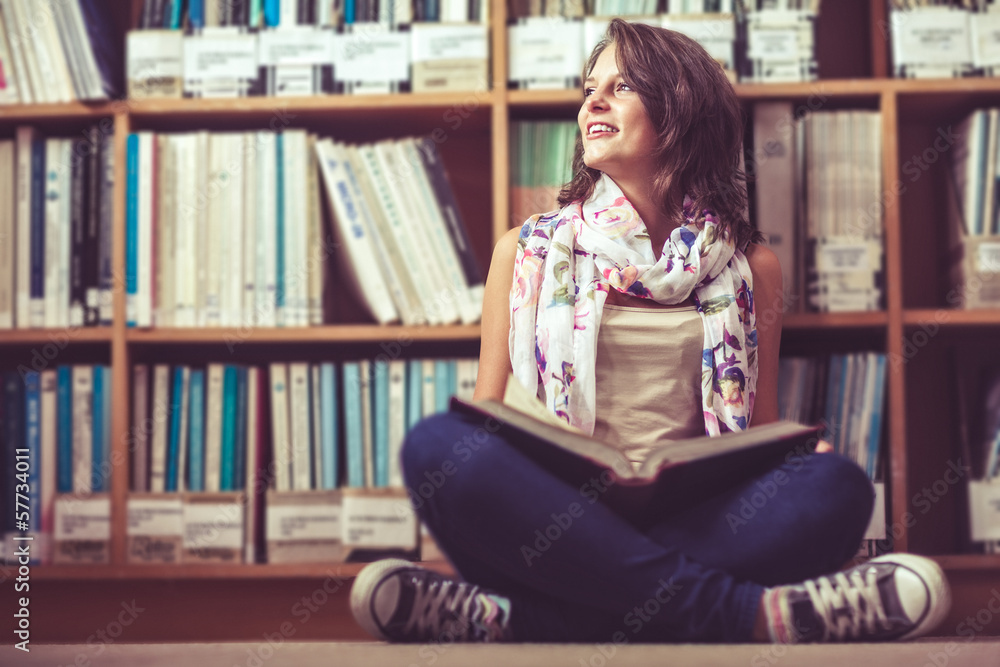 Thoughtful female student against bookshelf on the library floor Thoughtful female student against bookshelf on the library floor
