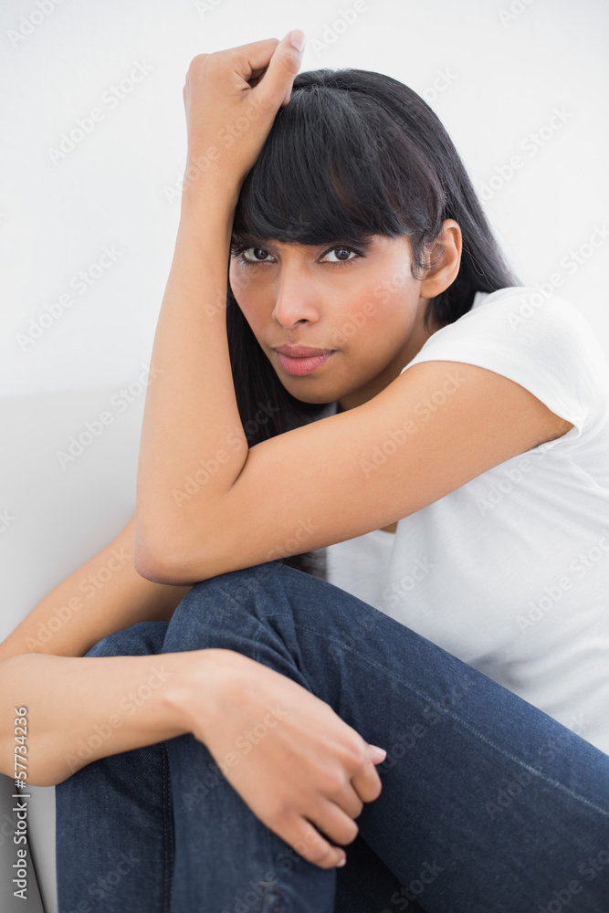 Beautiful thinking woman sitting on couch in bright living room Beautiful thinking woman sitting on couch in bright living room
