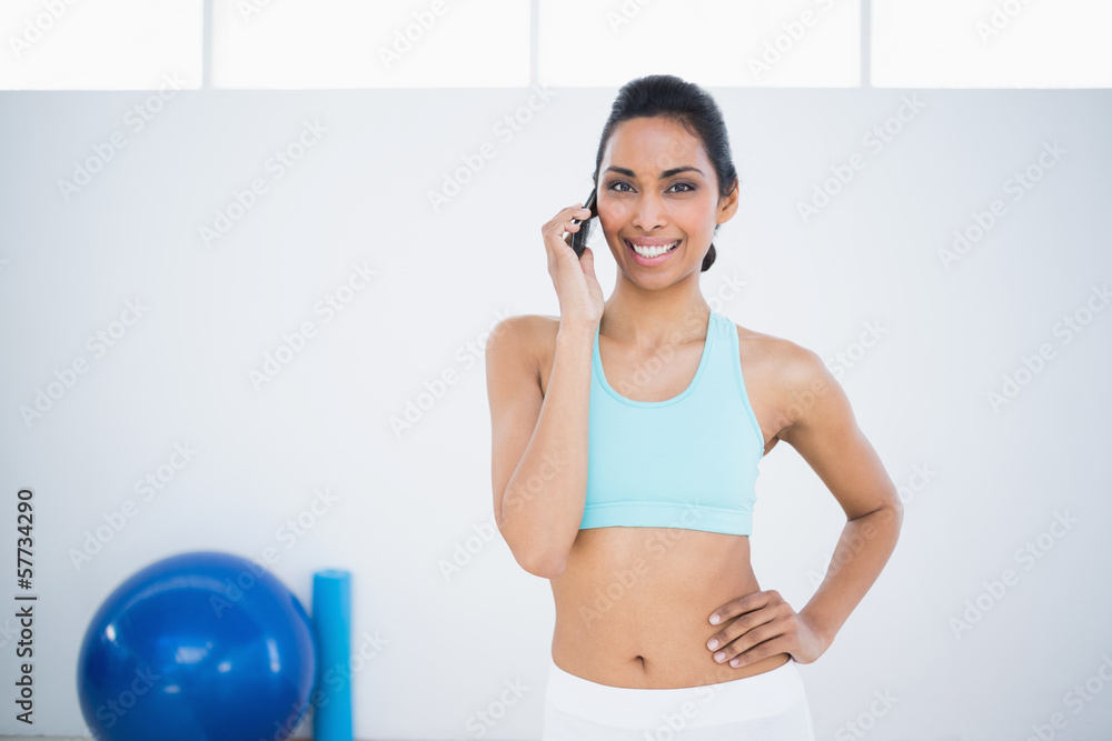 Gleeful sporty woman phoning while standing in fitness hall Gleeful sporty woman phoning while standing in fitness hall