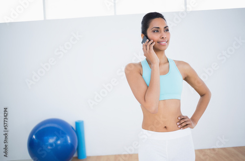Content smiling woman in sportswear phoning with smartphone