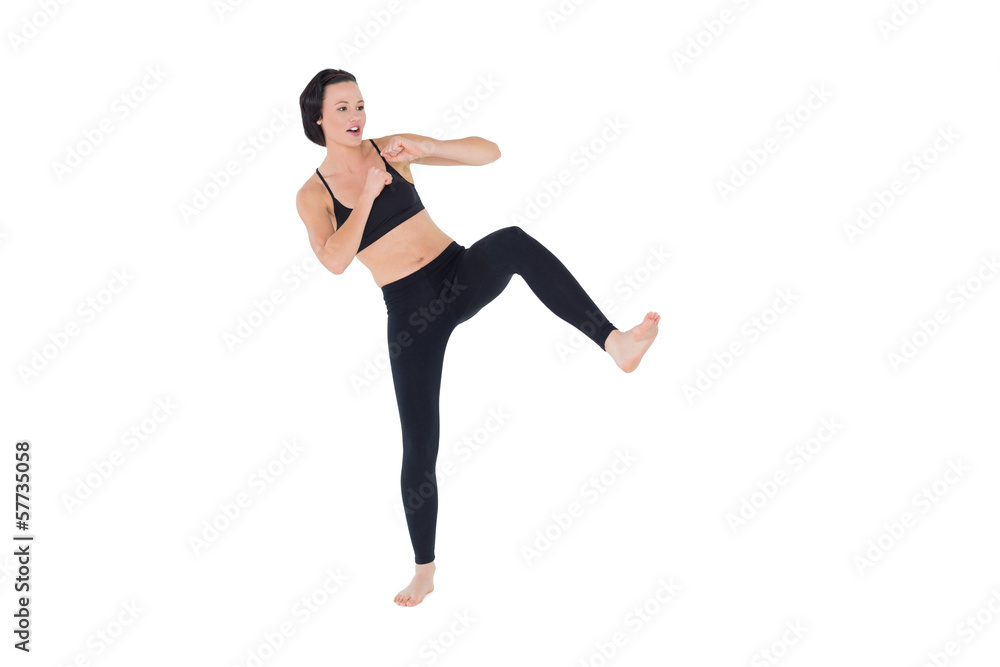 Full length of a sporty young woman air kicking