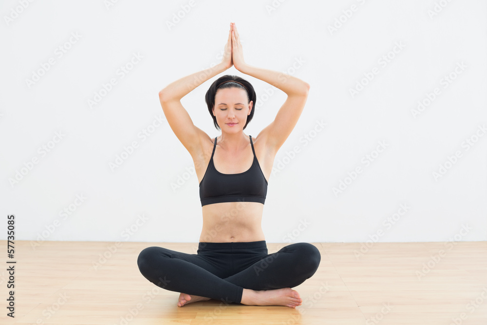 Woman in lotus pose with eyes closed at fitness studio