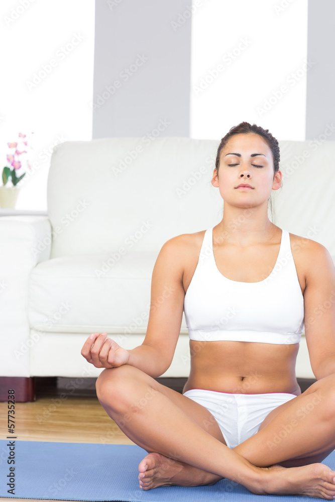 Brunette woman in sportswear sitting on an exercise mat Brunette woman in sportswear sitting on an exercise mat