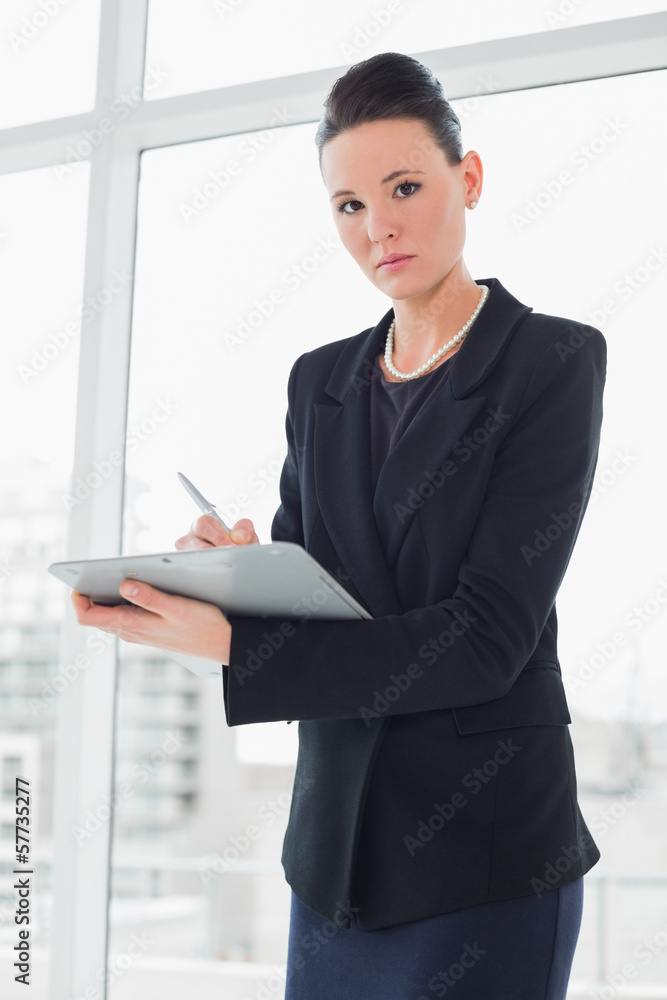 Elegant businesswoman writing notes in office Elegant businesswoman writing notes in office