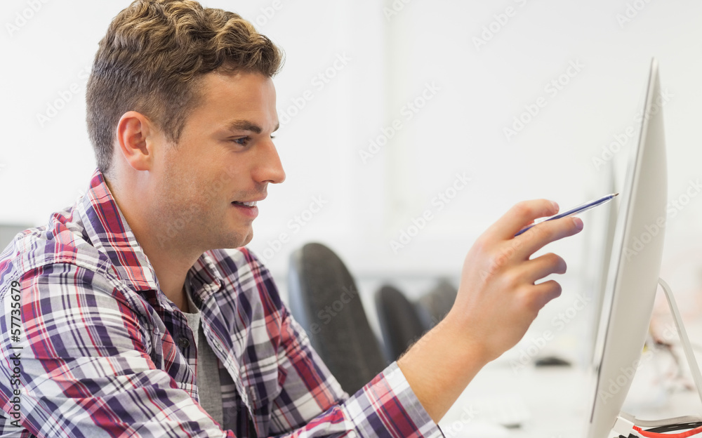 Handsome smiling student pointing at computer Handsome smiling student pointing at computer