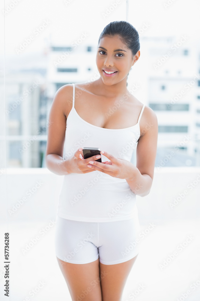 Happy toned brunette holding smartphone