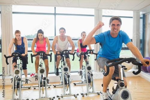 Happy man teaches spinning class to four people