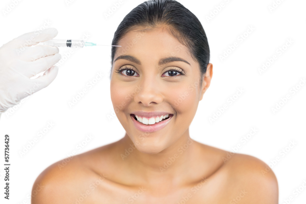 Smiling nude brunette holding injection looking at camera