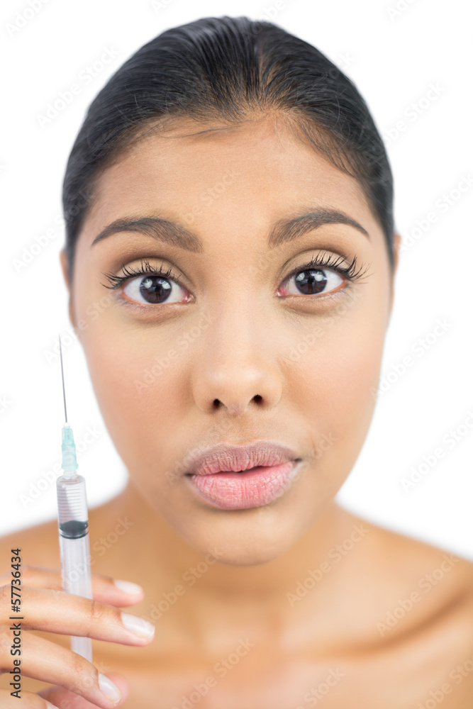 Unsmiling nude brunette holding injection