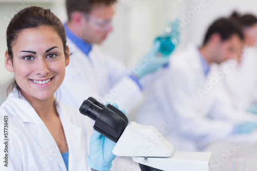 Smiling female with researchers working on experiments in lab