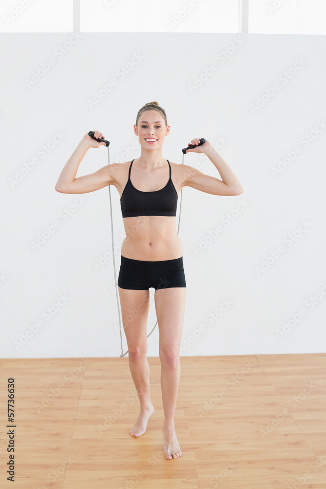 Gleeful slender woman holding a rope for skipping Gleeful slender woman holding a rope for skipping