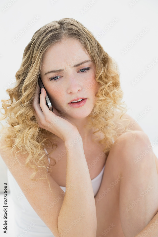 Pretty upset blonde sitting on bed phoning Pretty upset blonde sitting on bed phoning