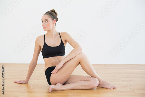 Cute toned woman stretching her body sitting on floor