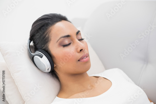 Lovely relaxing woman listening to music while lying on couch