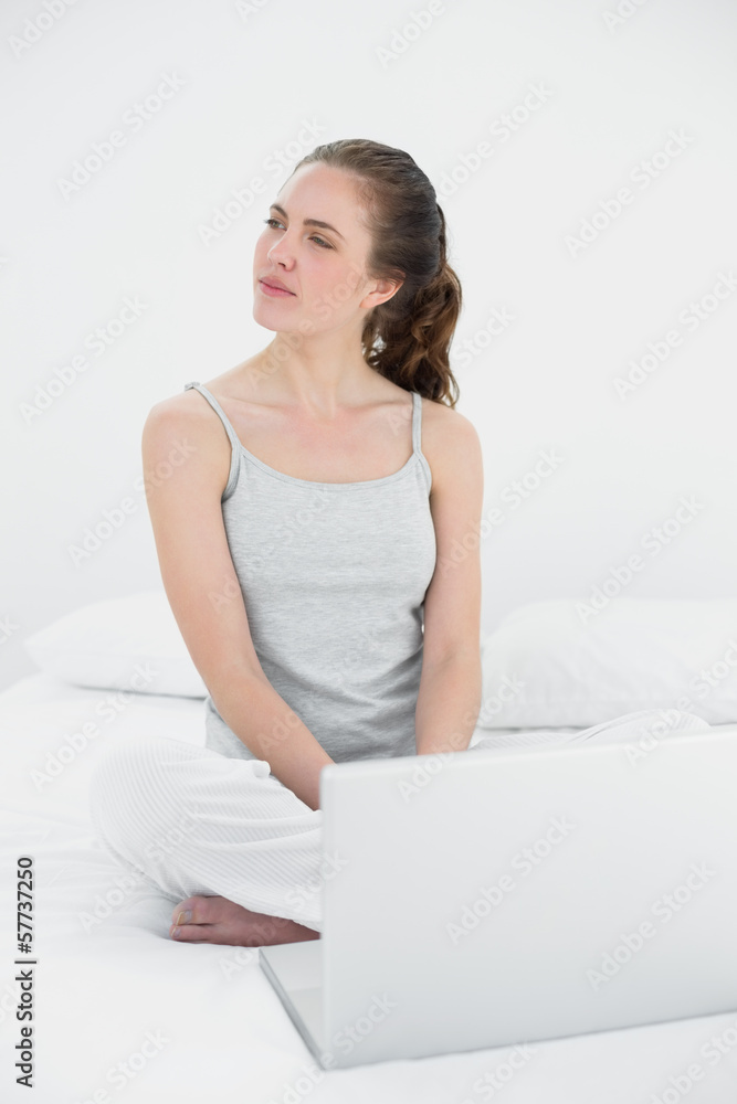 Casual woman with laptop looking to her side in bed Casual woman with laptop looking to her side in bed