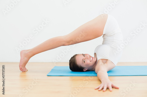 Side view of a smiling woman exercising on mat