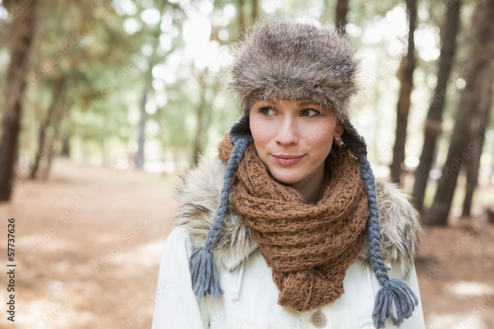 Woman wearing fur hat with woolen scarf and jacket in woods Woman wearing fur hat with woolen scarf and jacket in woods