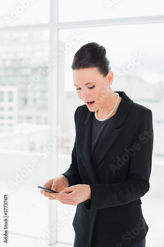 Shocked elegant businesswoman looking at mobile phone