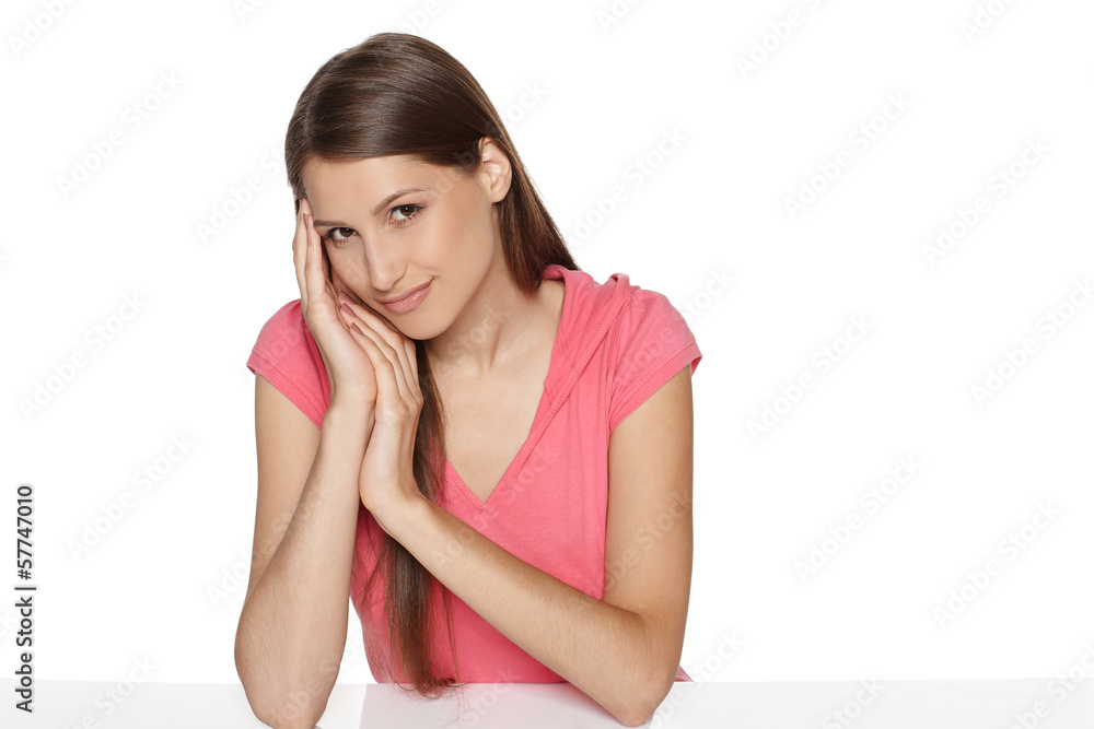 Cheerful female sitting at white table with head resting in hand Cheerful female sitting at white table with head resting in hand