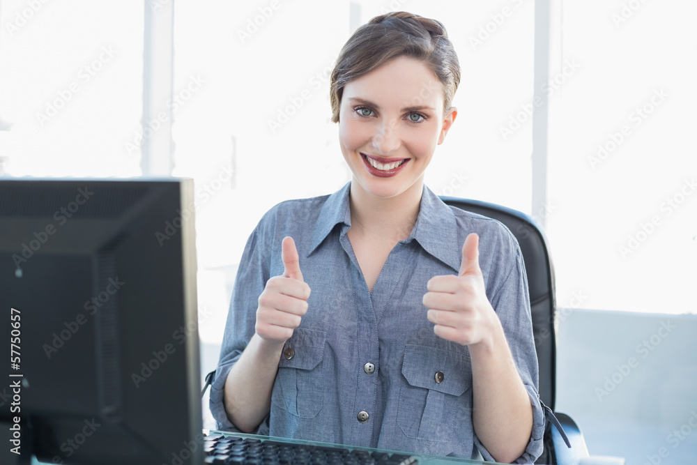 Cheerful businesswoman showing thumbs up sitting at he desk Cheerful businesswoman showing thumbs up sitting at he desk