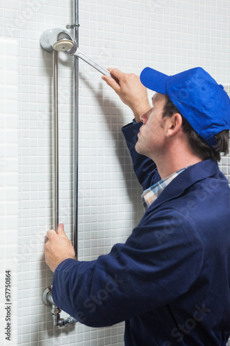 Fotografie Serious plumber repairing shower head
