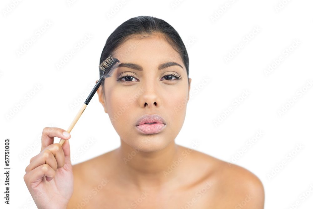 Serious nude brunette using eyebrow brush Serious nude brunette using eyebrow brush