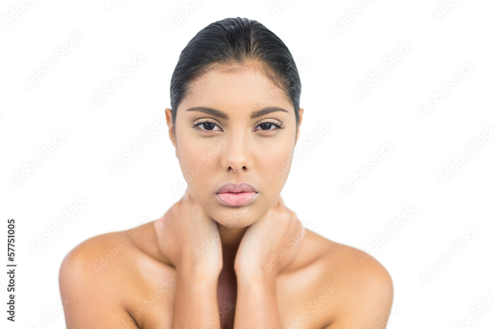 Frowning nude brunette holding her neck Frowning nude brunette holding her neck