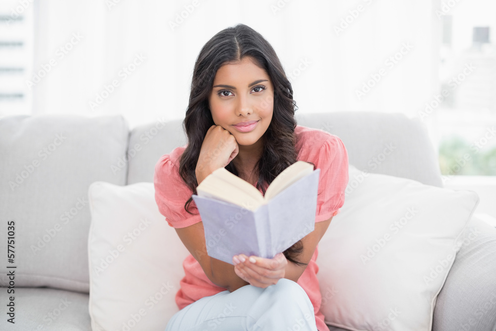 Happy cute brunette sitting on couch reading a book Happy cute brunette sitting on couch reading a book