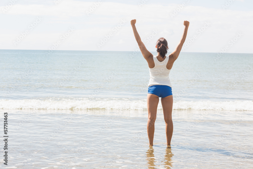 Lovely slim woman standing on beach raising her arms Lovely slim woman standing on beach raising her arms
