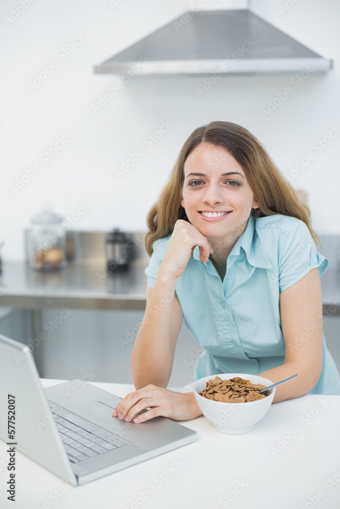 Gleeful woman using her laptop smiling at camera