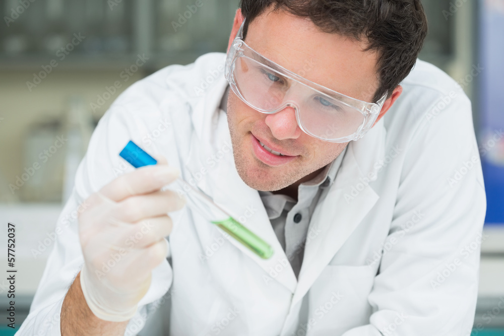 Scientist analyzing green solution in test tube at the lab Scientist analyzing green solution in test tube at the lab
