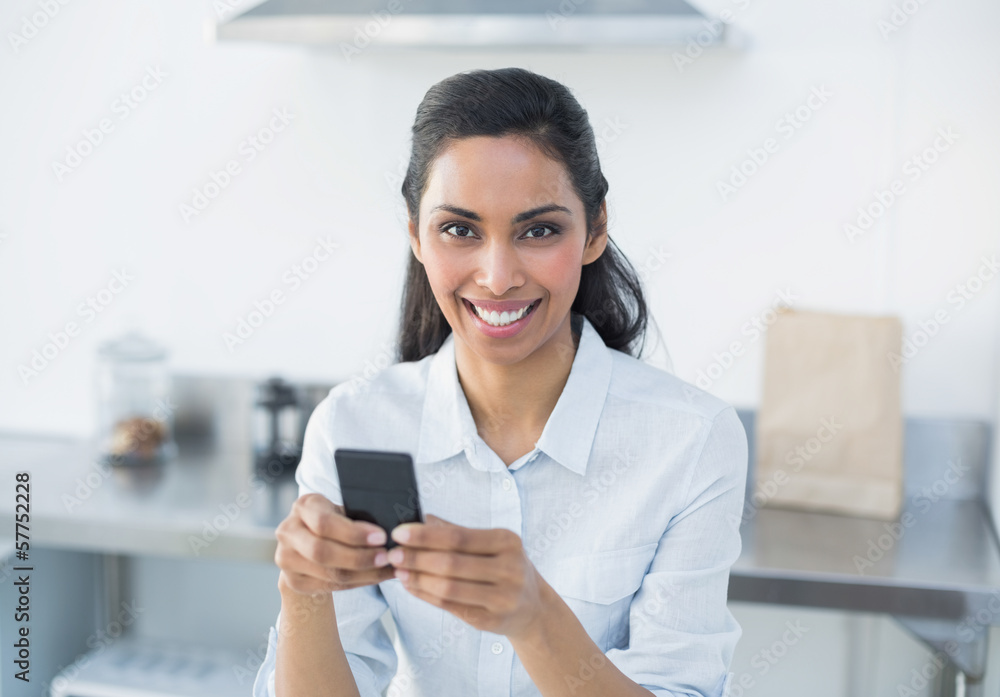 Natural smiling woman holding her smartphone looking at camera Natural smiling woman holding her smartphone looking at camera