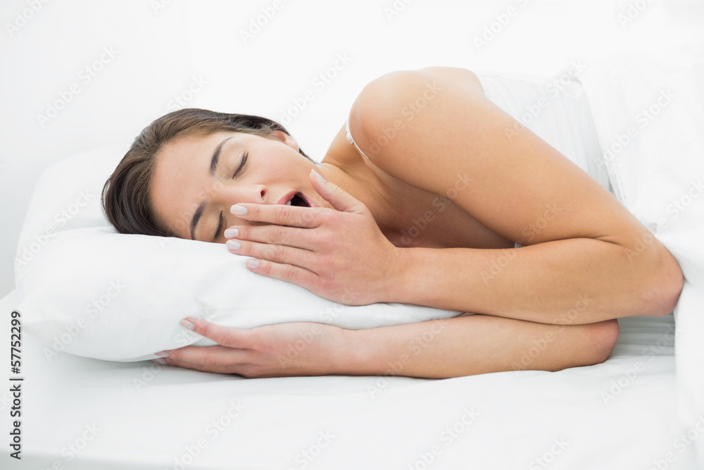 Fototapeta premium Young woman yawning in bed