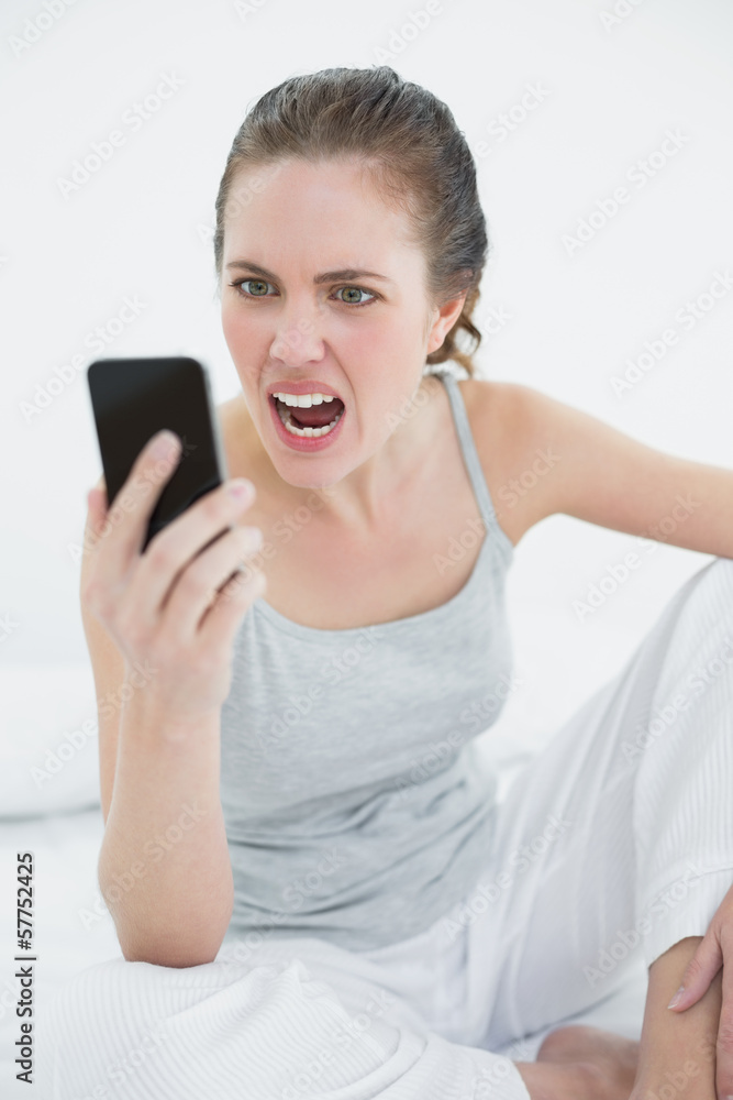 Woman shouting into mobile phone in bed Woman shouting into mobile phone in bed