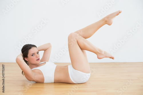 Sporty fit young woman doing sit ups in fitness studio