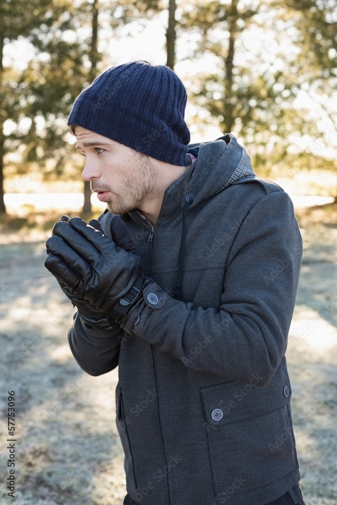 Man in warm clothing shivering while having a walk in forest Man in warm clothing shivering while having a walk in forest