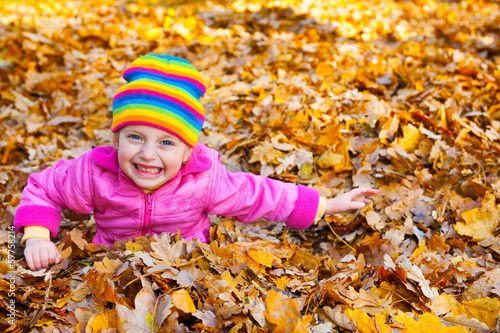 girl lies on yellow leaves in autumn park