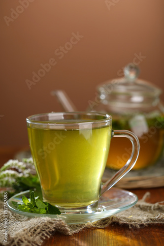 Cup and teapot of herbal tea with fresh mint flowers