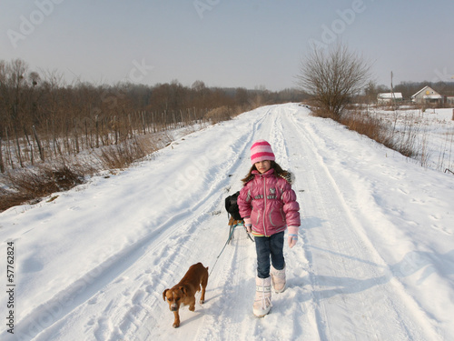 Girl and dog with sleigh walking on snow