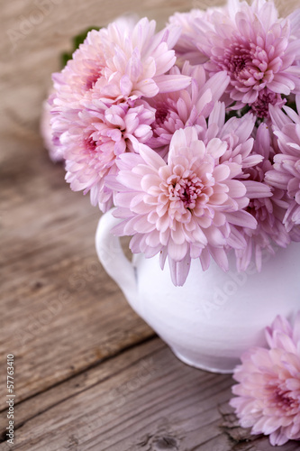 magenta flowers in a white vase on a wooden board