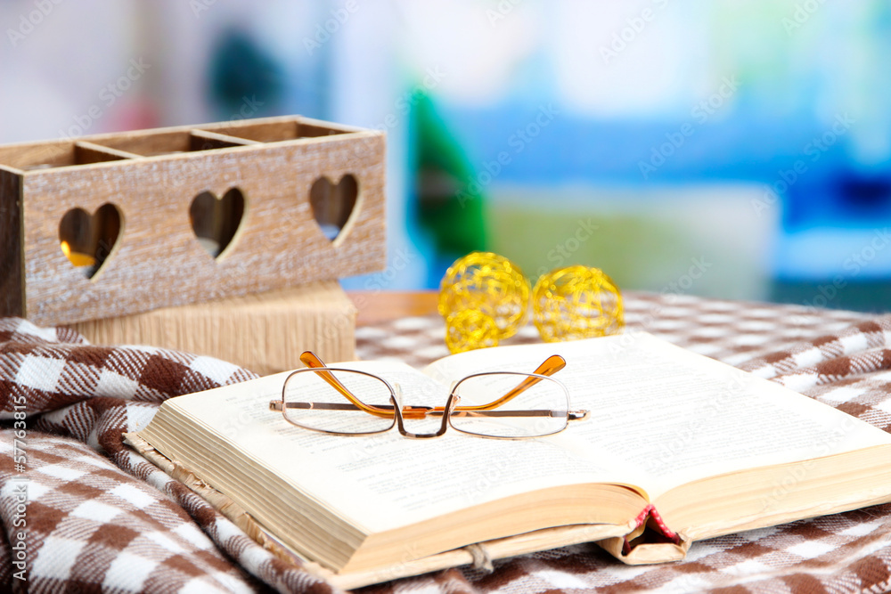 Composition with old book, eye glasses, candles, and plaid