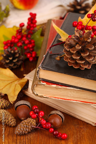 Books and autumn leaves on wooden table close-up