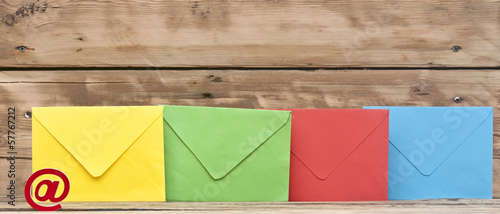 E-mail symbol and colorful envelopes on old wooden background