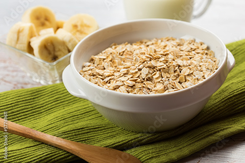 Oat flakes in bowl with banana and milk