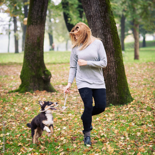 Young woman playing with Australian Shepherd dog outdoors in the
