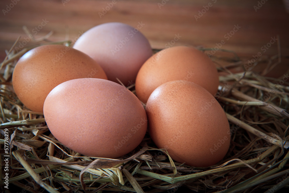 fresh eggs on rice straw with brown wood background