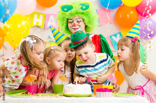 children with clown celebrating birthday party and blowing candl