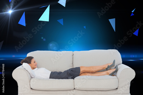 Composite image of smiling business woman lying down on the couc