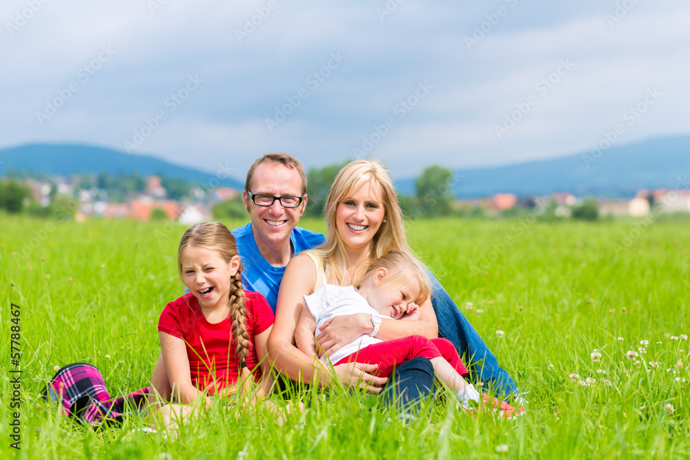 Glückliche Familie sitzt auf Wiese im Sommer Glückliche Familie sitzt auf Wiese im Sommer